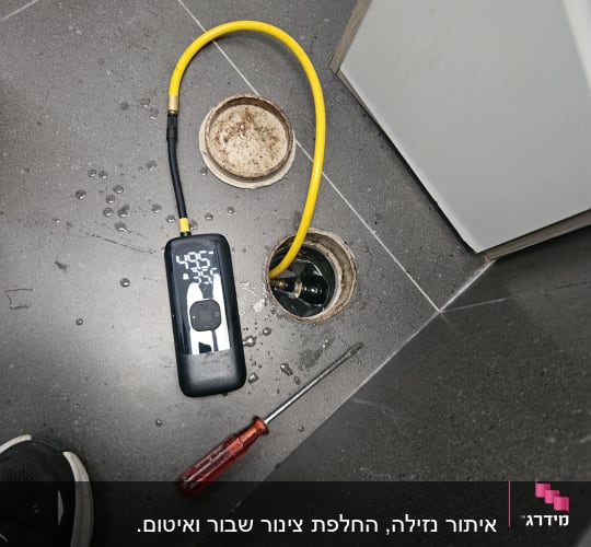 כלי עבודה וצינור ליד פתח ניקוז ברצפה
